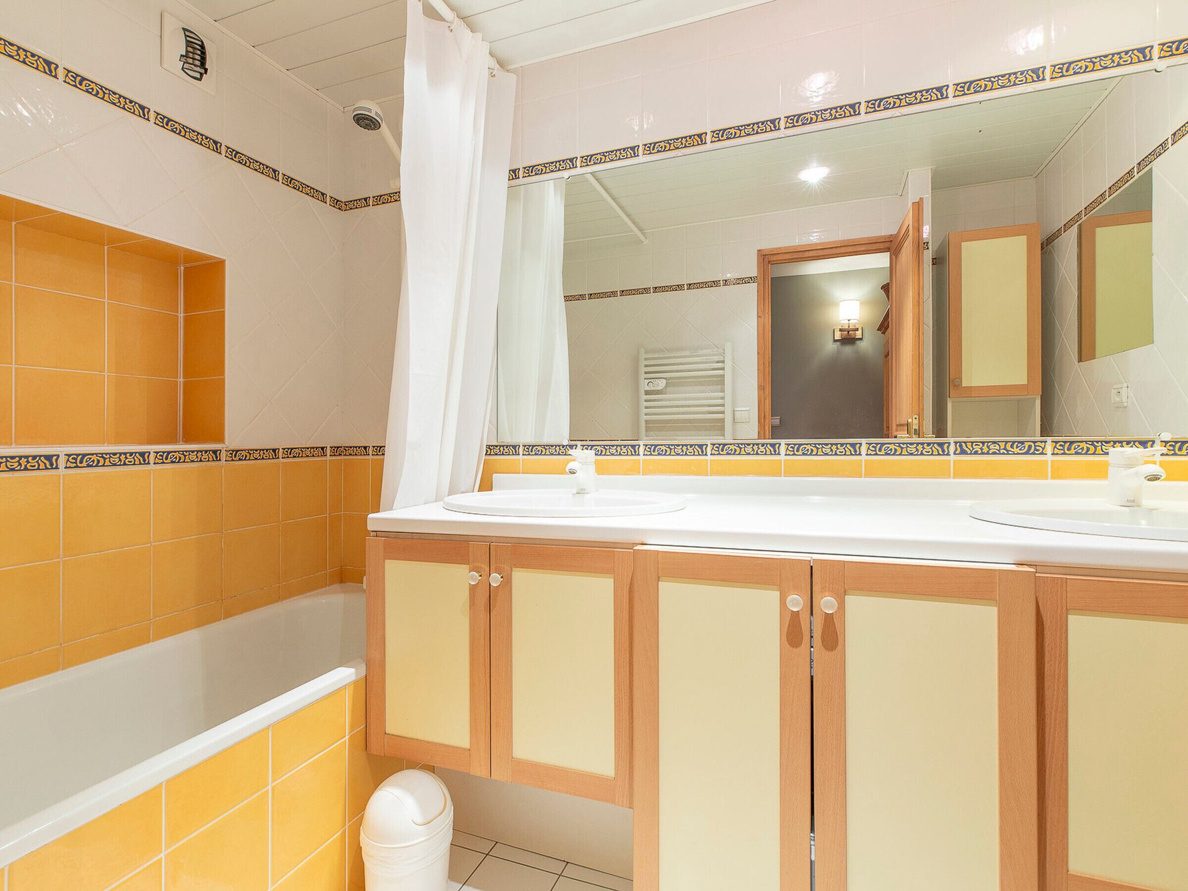 Une salle de bain avec un lavabo blanc, des meubles en bois et un espace douche.