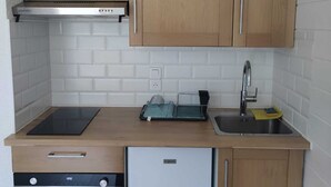 A compact kitchen with wooden cabinets, a stainless steel range hood, a dishwasher, and a sink with a faucet.