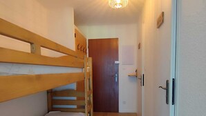 A narrow hallway with bunk beds on one side and a door at the end.