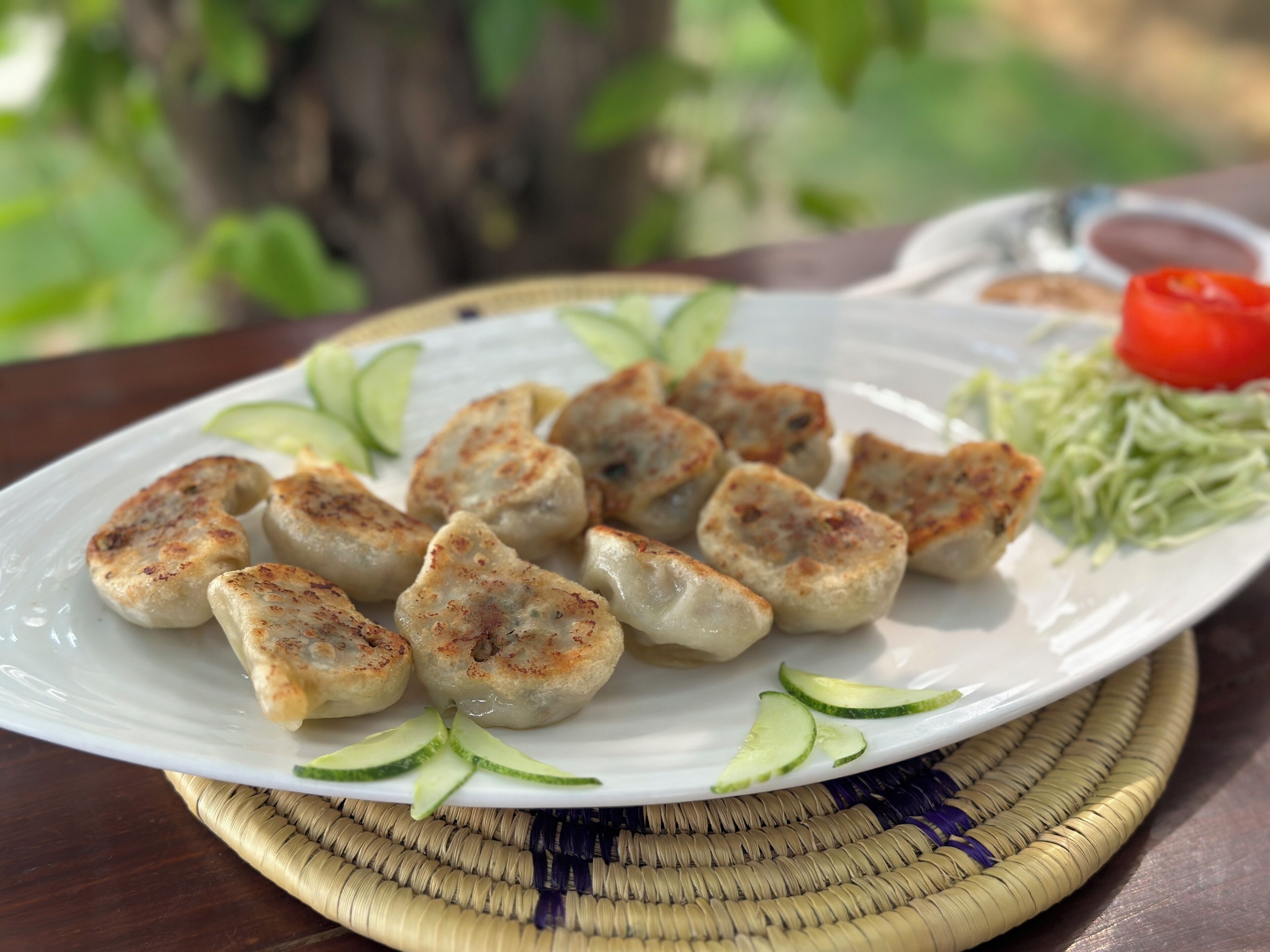 Ein Teller gegrillte Hackbällchen mit Gurkenscheiben und einer kleinen Soße.