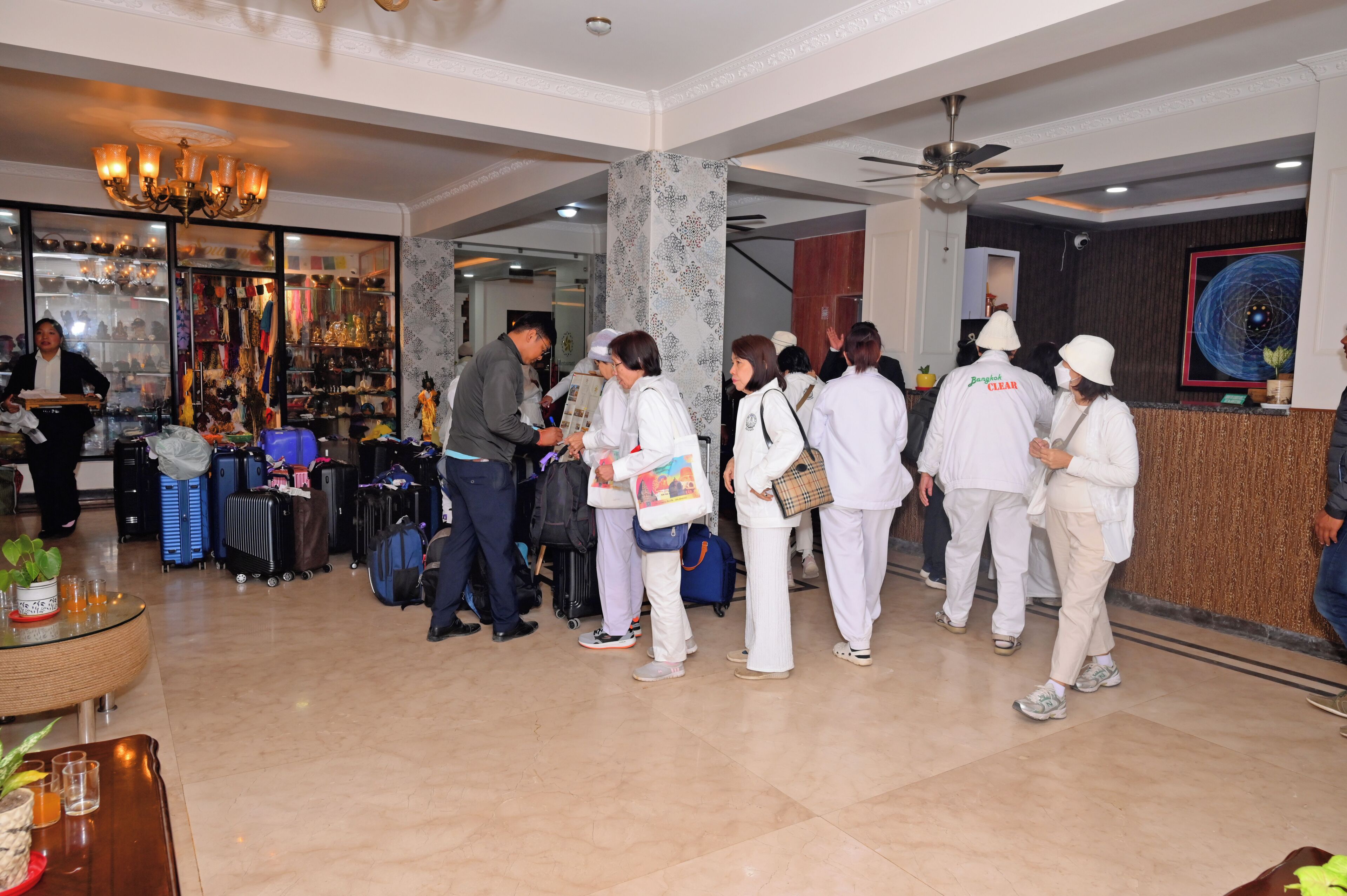 A hotel lobby with a reception desk, a chandelier, and a wall with a decorative pattern.