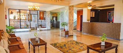 A spacious lobby with a reception desk, seating area, and a chandelier.