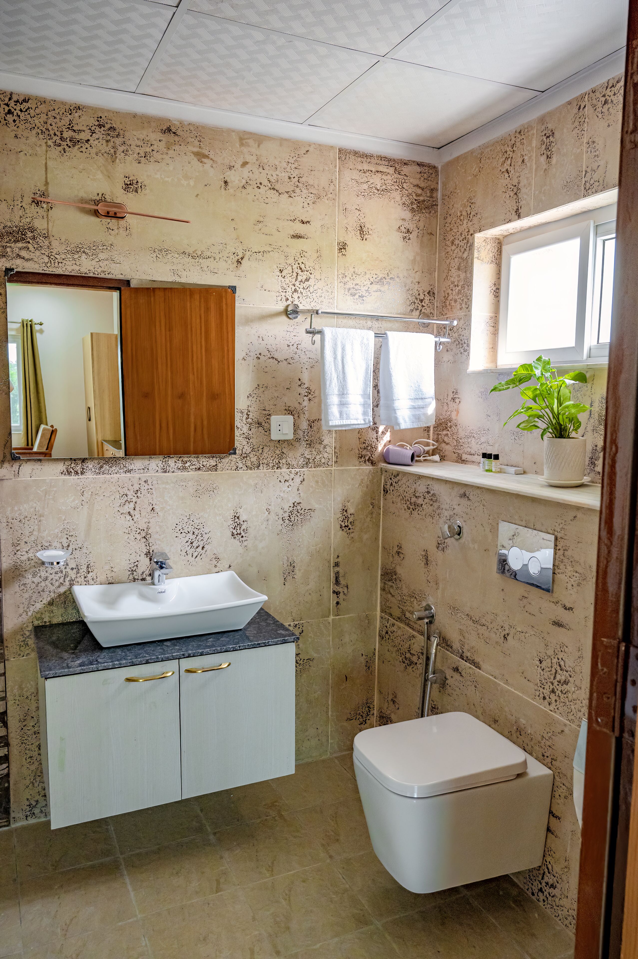 Ein Badezimmer mit weißem Waschbecken, Toilette, Dusche, Spiegel und Fenster.
