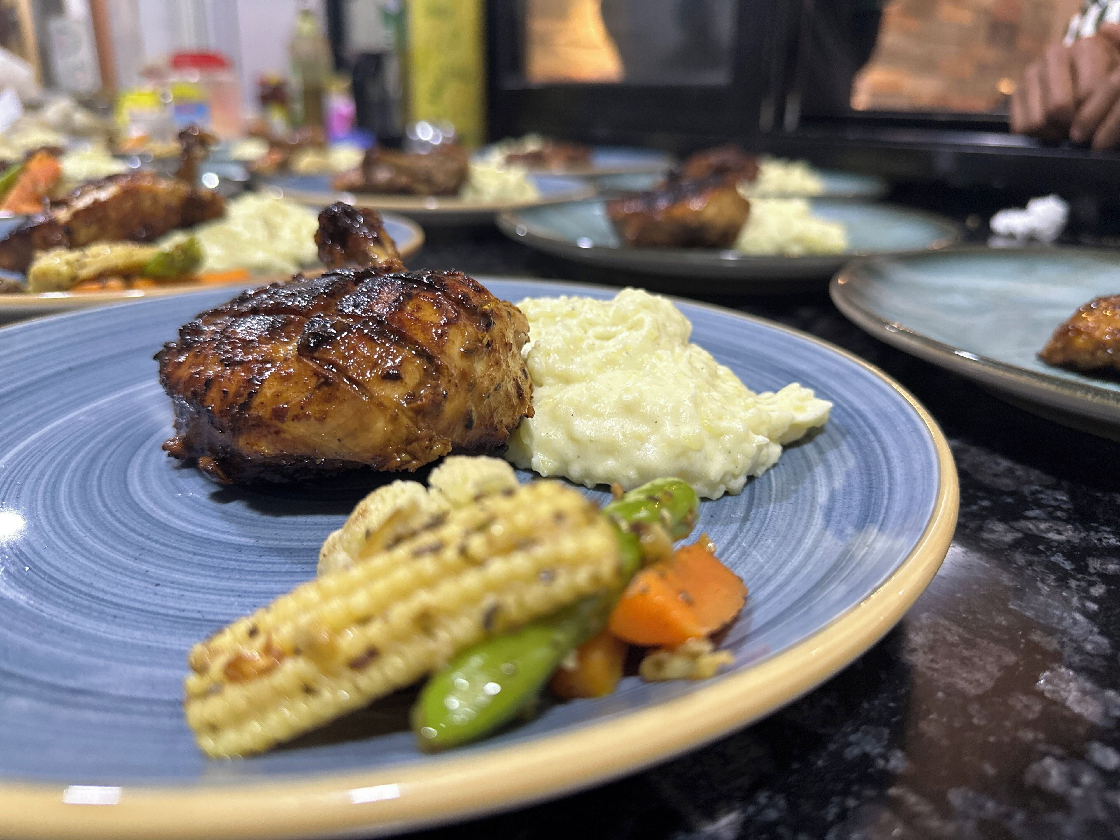 A plate with grilled meat, mashed potatoes, corn, and carrots.