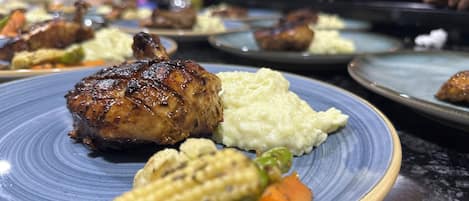 A plate with grilled meat, mashed potatoes, corn, and carrots.