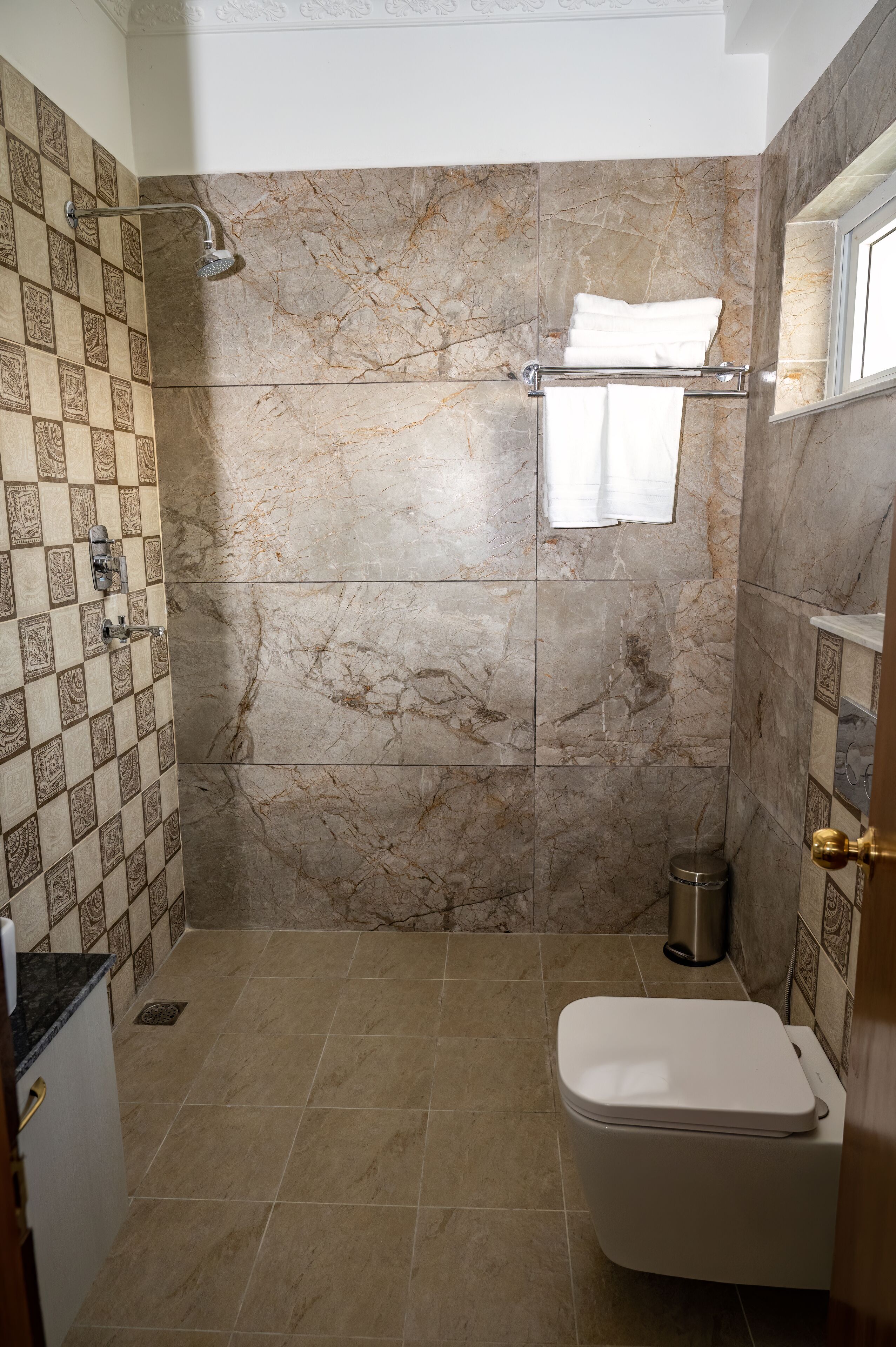 Un baño con ducha, inodoro y pared de azulejos.