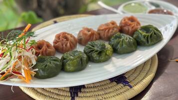 Un plato de dumplings acompañado de verduras ralladas y salsa para mojar.