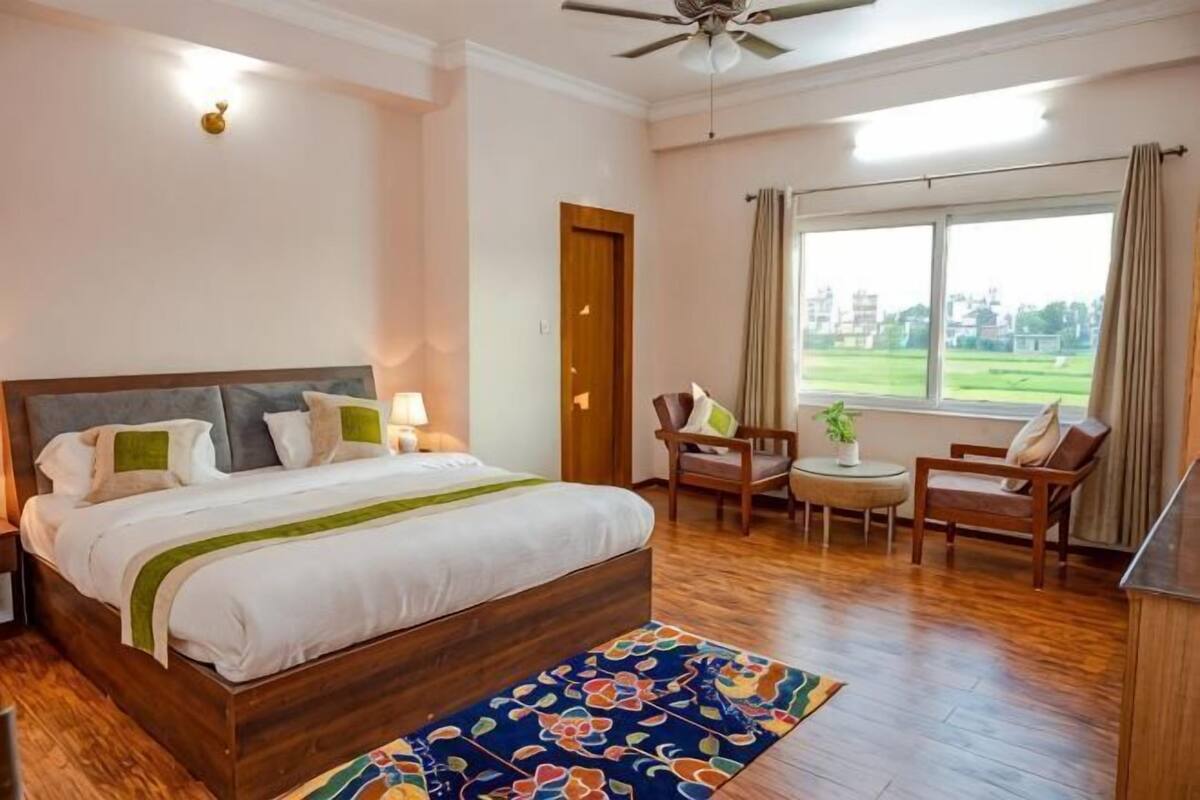 A bedroom with a bed, bedside tables, a chair, a small table, and a window with a view.