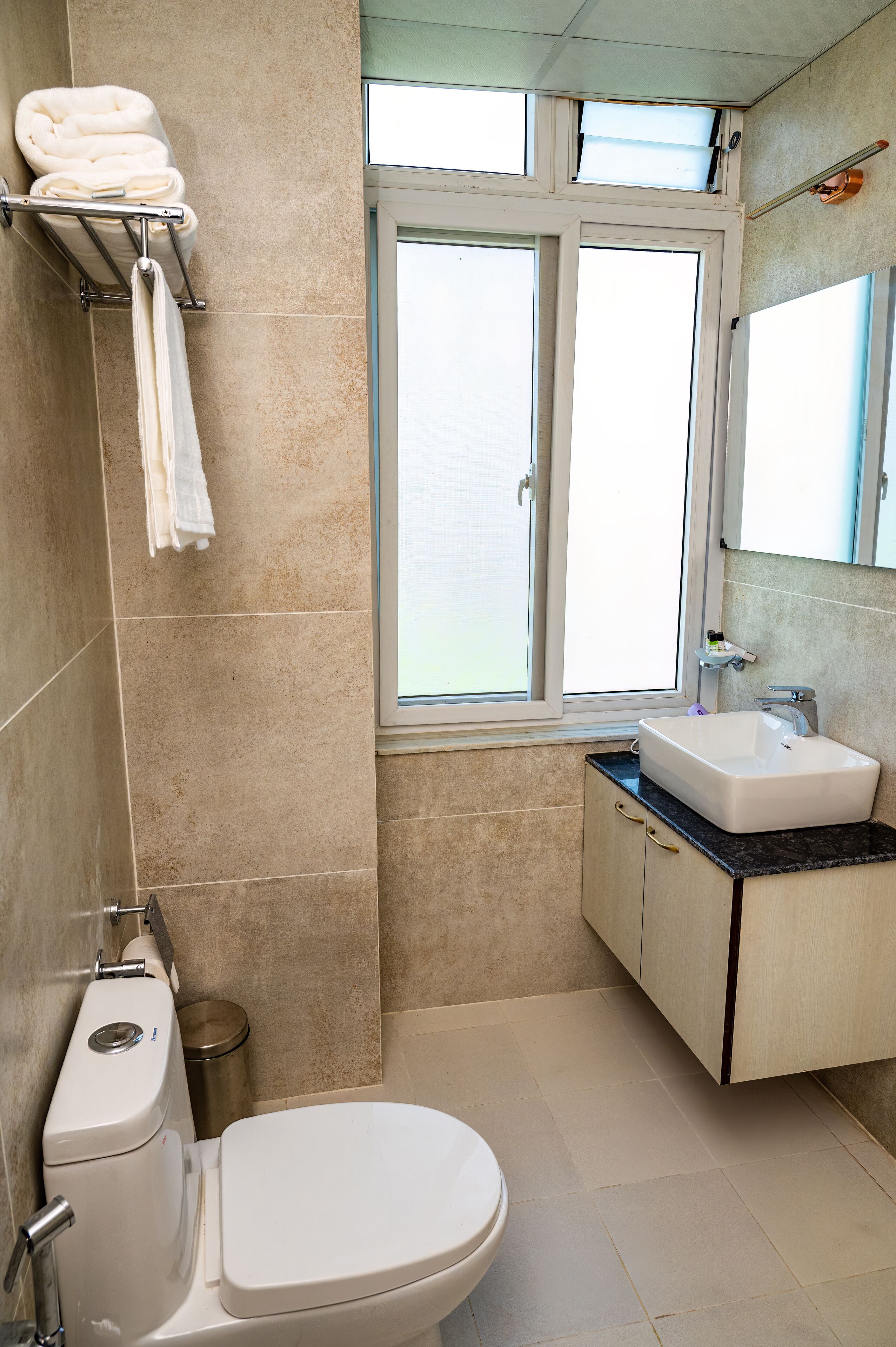 A bathroom with a toilet, sink, and window.