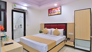 A hotel room with a bed, bedside table, wardrobe, and a shower area. - Hotel Hari International (Noida)