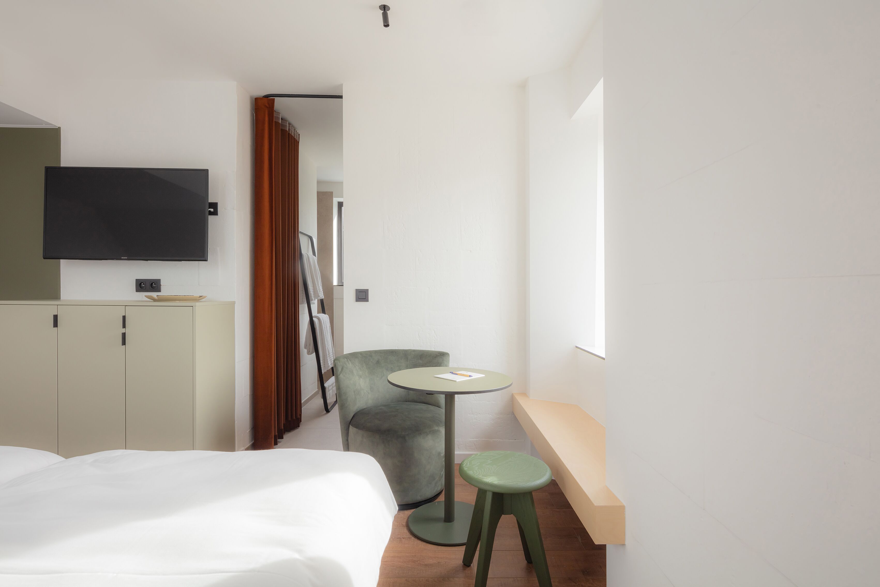 Une chambre d’hôtel avec un lit, un bureau, une chaise, une télévision et une fenêtre.