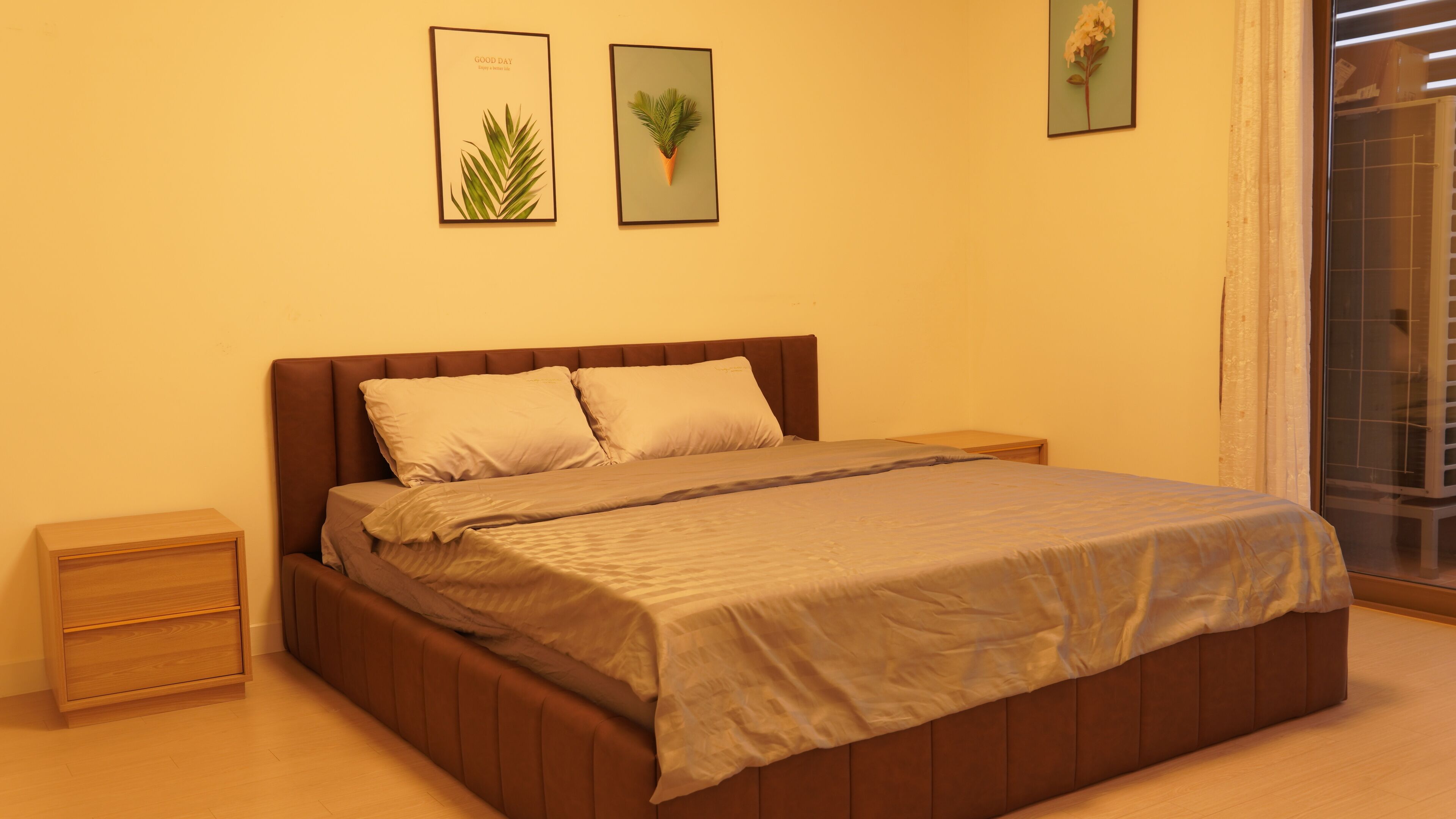 A bedroom with a bed, nightstands, and two framed pictures on the wall.