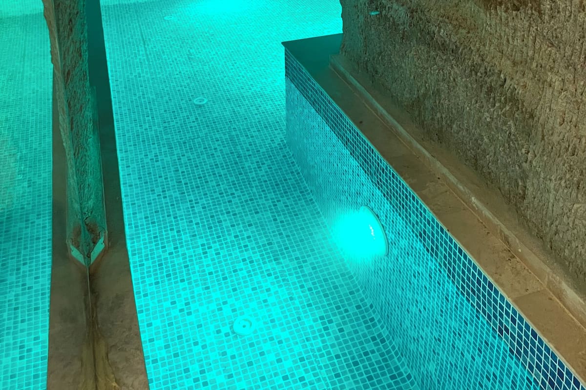 A stone-walled pool with a tiled floor and a clear blue waterline.
