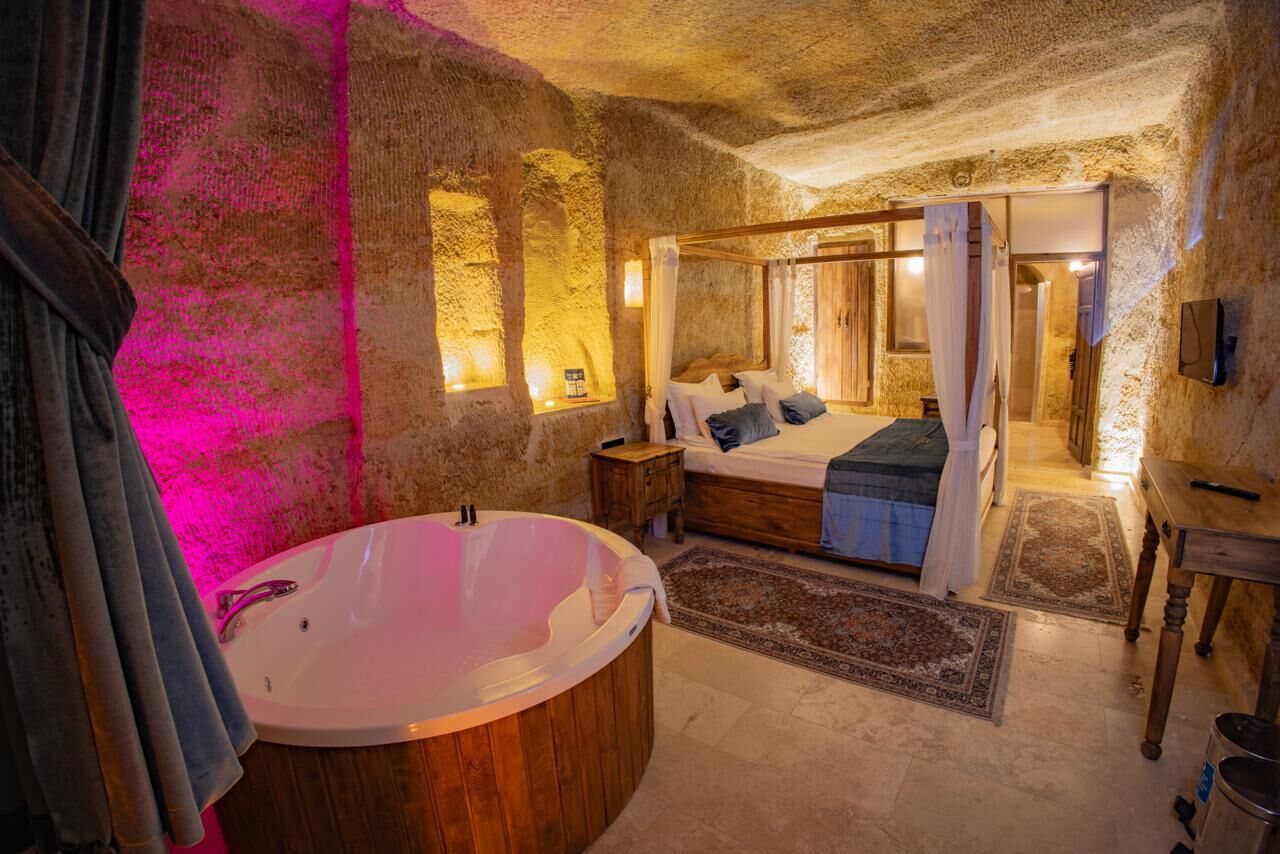 A bedroom with a large wooden bathtub, a bed with a canopy, and a stone wall.