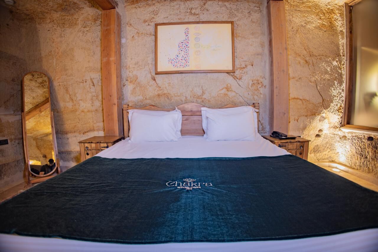 A bed with a dark blue blanket and a framed artwork above it.
