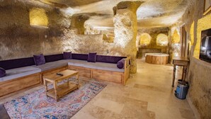 A cozy interior with a wooden sofa set, a small table, and a patterned rug. - Chakra Special Caves (Ürgüp)