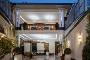Ein prachtvoller Eingangsbereich mit Balkon, einer Chandelierleuchtre und einer Sitzgruppe mit Sonnenschirm.