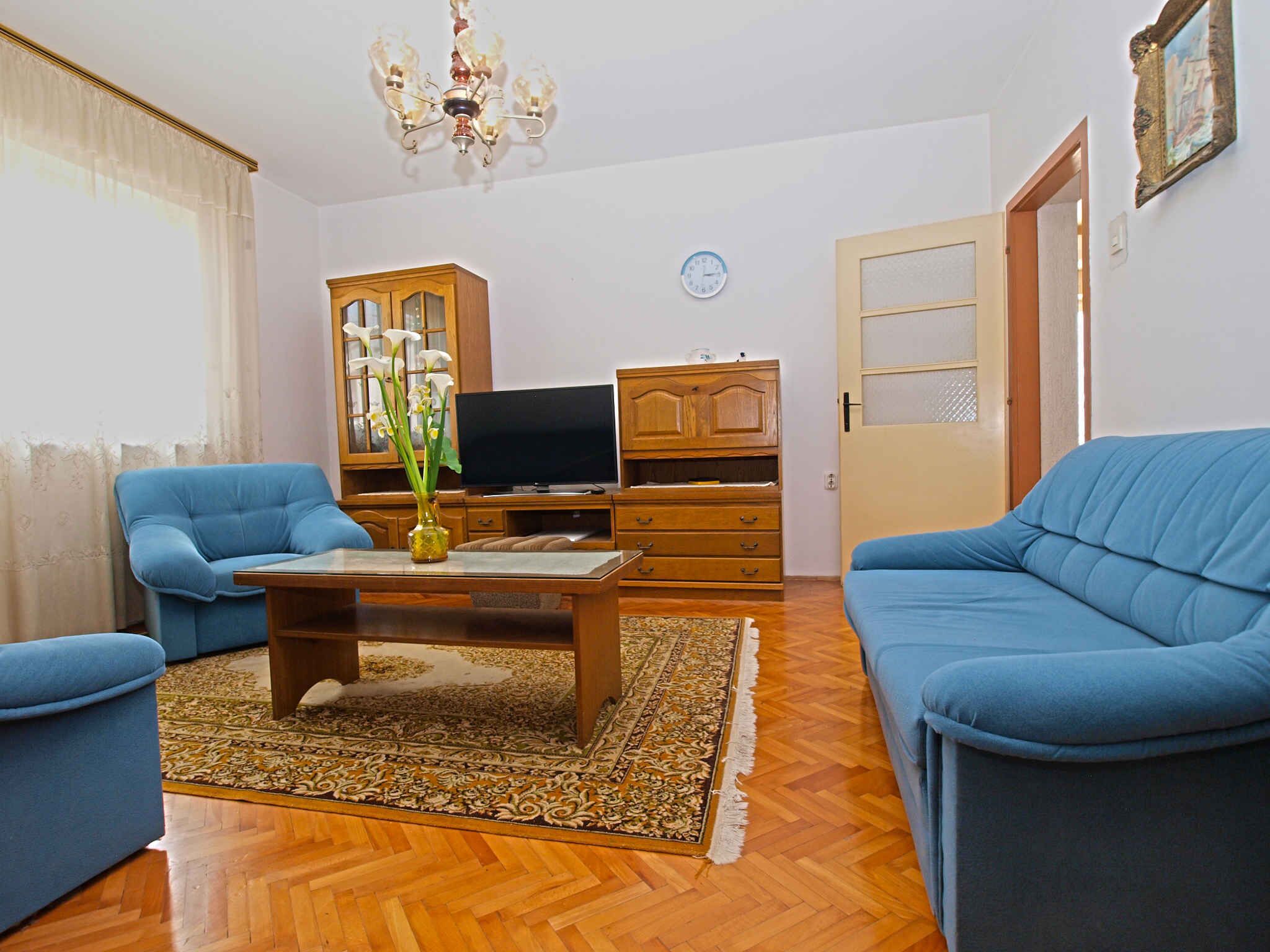 Una sala de estar con dos sofás azules, una mesa de centro de madera, un televisor y un armario.