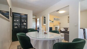 A dining area with a round table, green chairs, and a glass cabinet with dishes. - Holiday apartment with air conditioning (Pula)