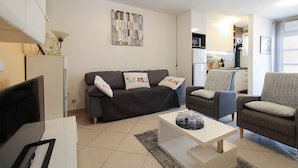 A living room with a sofa, armchairs, a coffee table, and a TV. - Holiday apartment with air conditioning (Pula)