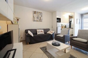 A living room with a sofa, armchairs, a coffee table, and a TV. - Holiday apartment with air conditioning (Pula)