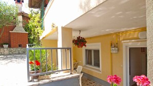 A building with a yellow facade, a stone staircase leading to a door, and a metal railing. - Holiday apartment with air conditioning (Pula)