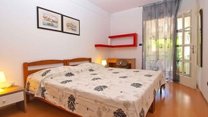 A bedroom with a bed, a nightstand, a desk, a chair, and a window with curtains. - Holiday apartment with air conditioning (Pula)