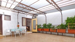 A covered patio area with a table and chairs, potted plants, and a door leading to an adjacent room. - Holiday apartment with air conditioning (Pula)