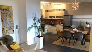 A modern kitchen with a dining area, a potted plant, and a chandelier. - Apartment With Amazing Lake- and Mountain View (Kaisigen)