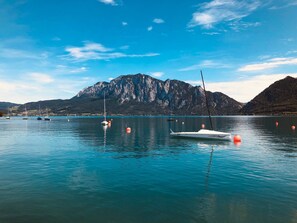 A calm lake with boats, a mountain in the background, and clear skies. - Apartment With Amazing Lake- and Mountain View (Kaisigen)