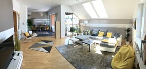 Un vaste espace de vie comprenant un canapé, une table basse et un coin repas avec des chaises.