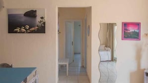 A room with a bed, a desk, and a chair. There is a door leading to another room. - Holiday apartment With a view of the sea (Golfo Aranci)