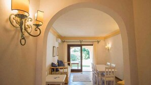 Quarto com área de jantar, um sofá e vista por um arco.