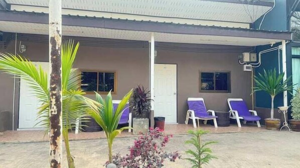 A covered outdoor area with two lounge chairs and a door.