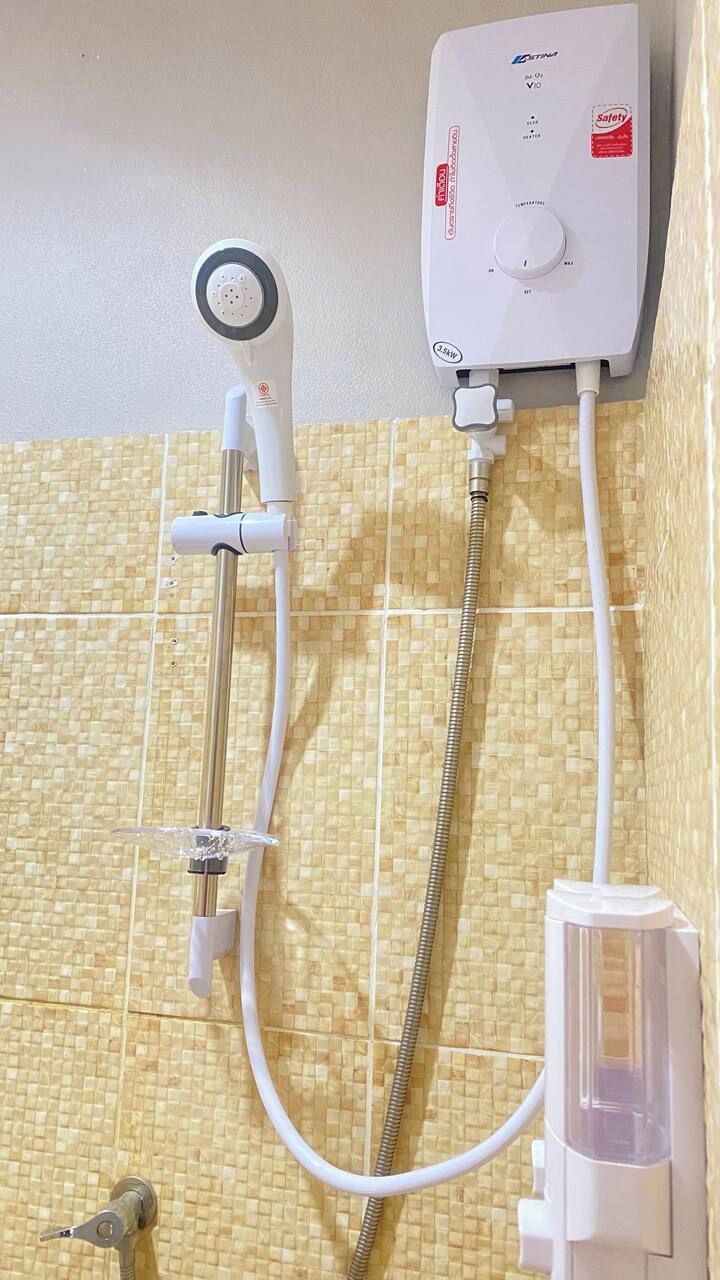 A wall-mounted shower unit with a control panel, a handheld showerhead, and a handheld shower attachment.
