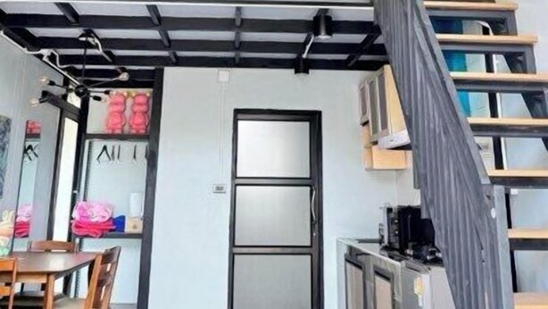 A modern interior with a high ceiling, a staircase, and a dining area.