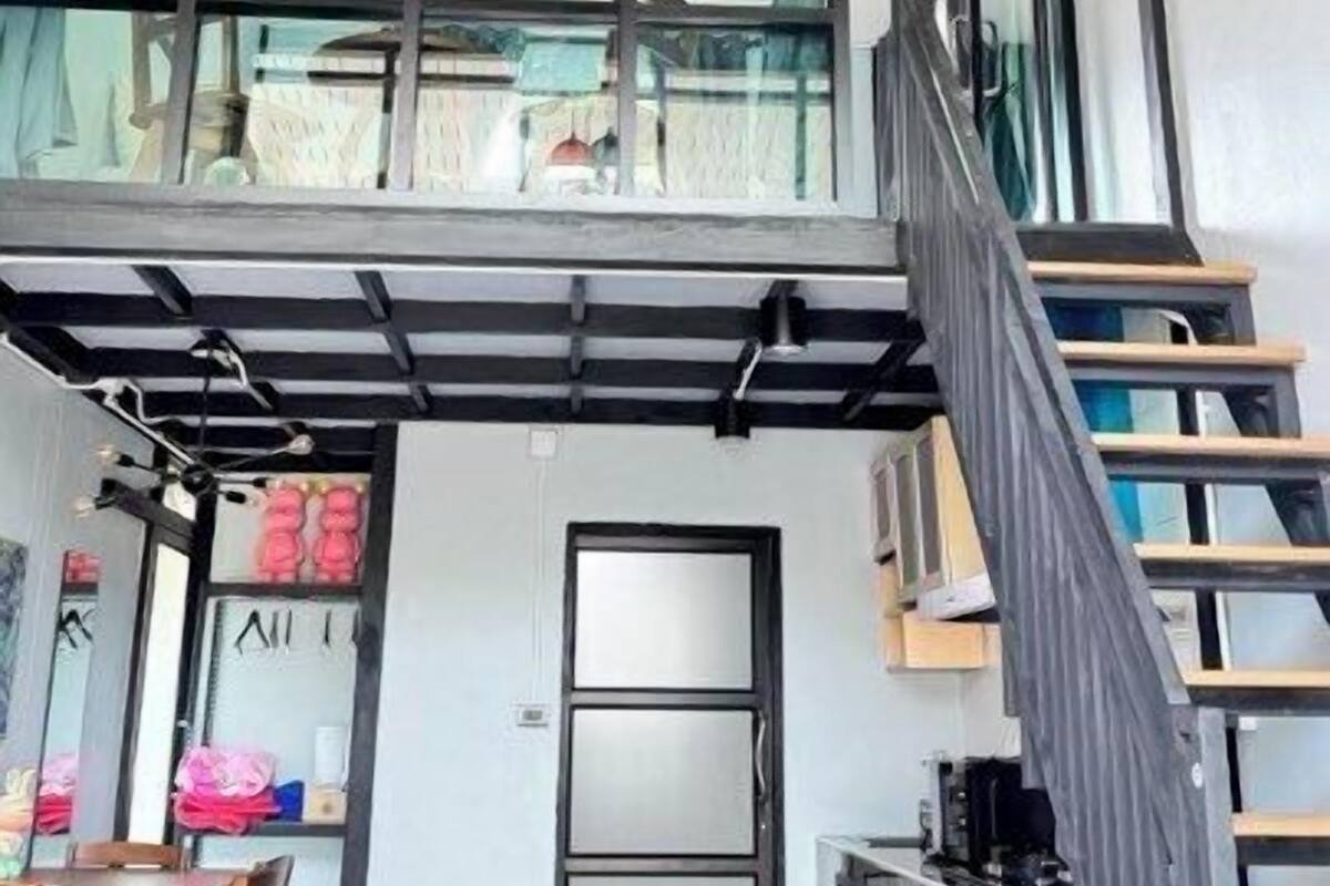 A modern interior with a high ceiling, a staircase, and a dining area.