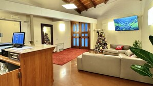 Un salón espacioso con techo de madera, un televisor de pantalla plana grande montado en la pared, un sofá y un árbol de Navidad.