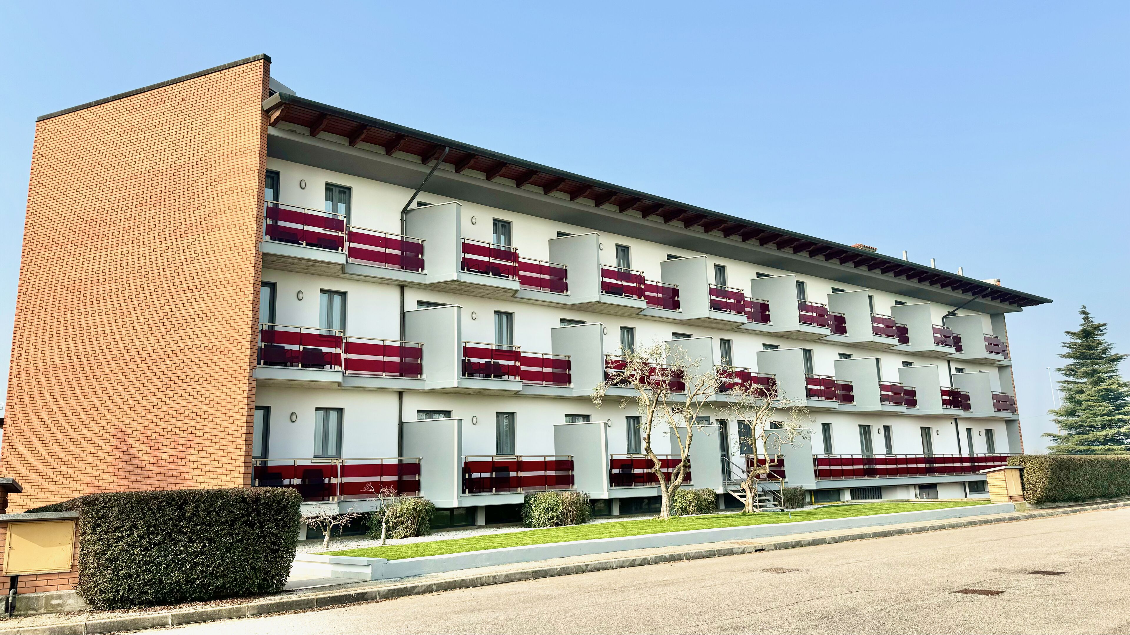 A multi-story hotel with balconies, a brick facade, and a well-maintained lawn.