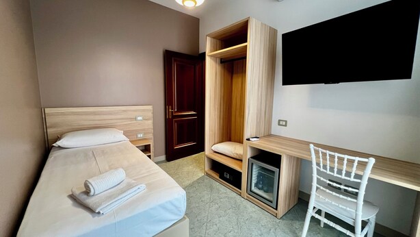 A bedroom with a bed, a desk, a chair, a wardrobe, and a TV. - HC Hotel Touring Seniga (Seniga)