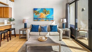 A living room with a sofa, coffee table, and a painting of a beach scene.