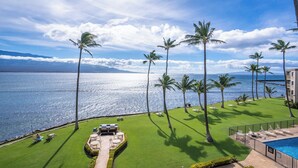 A resort with a pool, lawn chairs, and palm trees.