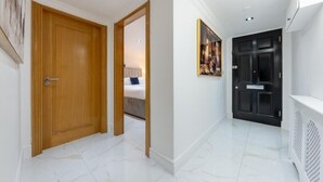 Un couloir avec une porte en bois, une porte noire et un radiateur blanc.