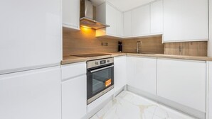 Une cuisine moderne avec des meubles blancs, un four en acier inoxydable et un plan de travail en bois.