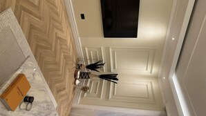 A room with a herringbone wood floor, a white door, and a black framed artwork on the wall. - Luxury One-bedroom in Central London (London)