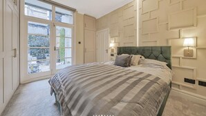 A bedroom with a large bed, a sliding glass door to the outside, and a wall with geometric paneling. - Luxury One-bedroom in Central London (London)