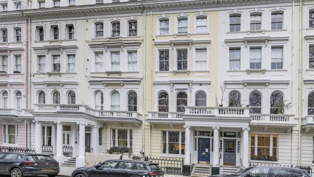 A row of white townhouses with multiple stories, each featuring a balcony and a front door. - Luxury One-bedroom in Central London (London)