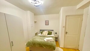 Ein Schlafzimmer mit Bett, Nachttisch, Kleiderschrank und einer Tür.