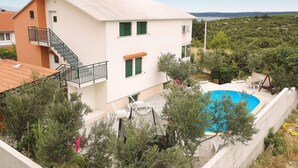 Une maison à deux étages dotée d’un balcon, d’une piscine et offrant une vue sur le paysage environnant.