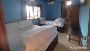 Una habitación con dos camas, ventilador de techo y ventana con cortinas.